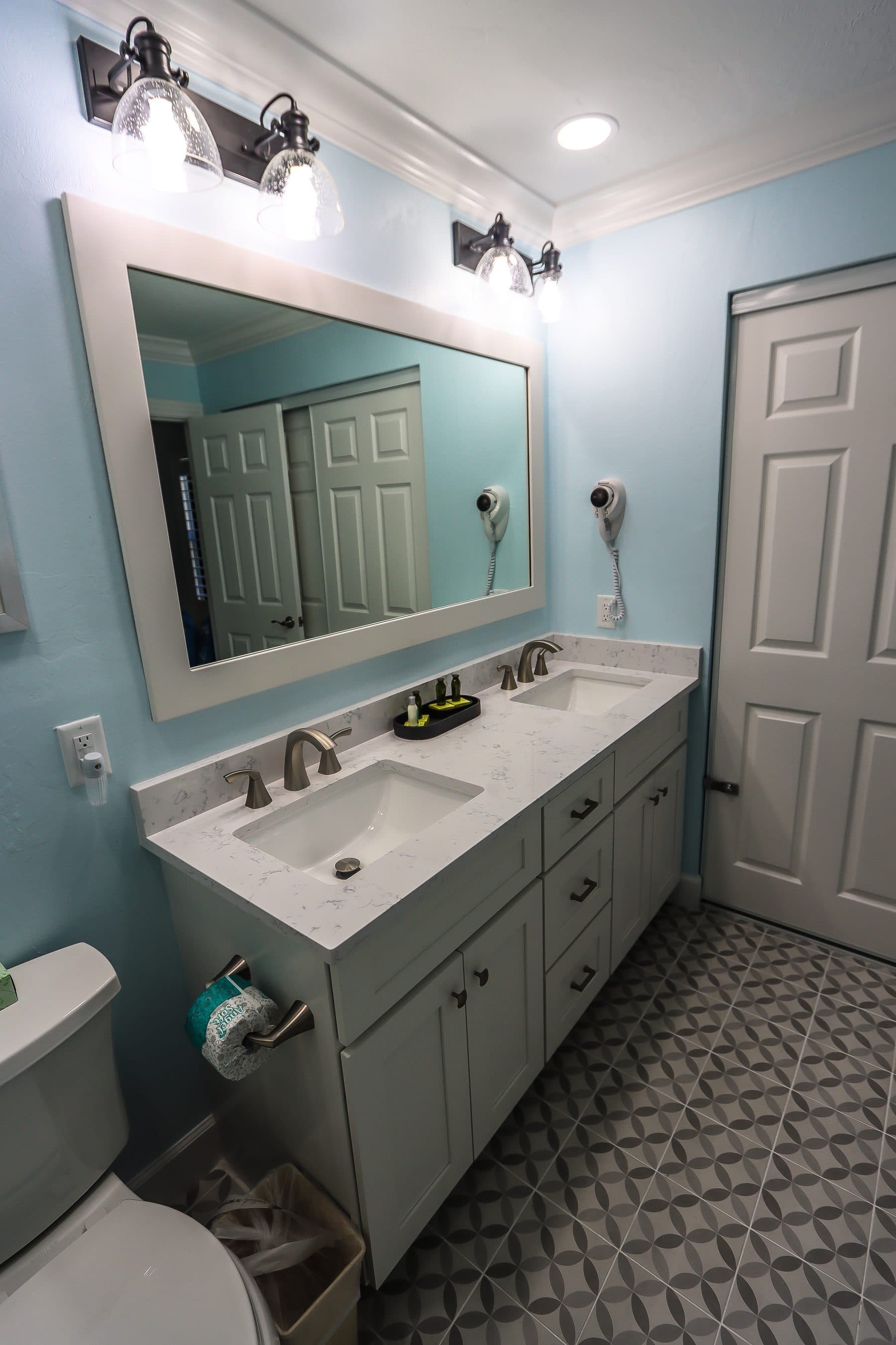 Finished bathroom with double vanity and patterned tile floor